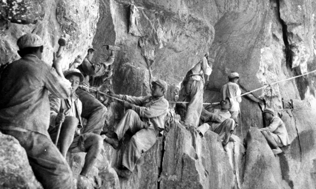 1954年，修筑康藏公路的解放軍戰(zhàn)士們在怒江兩岸的懸崖陡壁上辟山筑路。新華社稿 李萬春、張加里攝